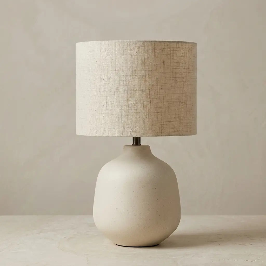 Ivory ceramic table lamp with a cylindrical fabric shade, front view