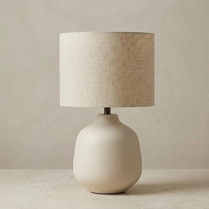 Ivory ceramic table lamp with a cylindrical fabric shade, front view