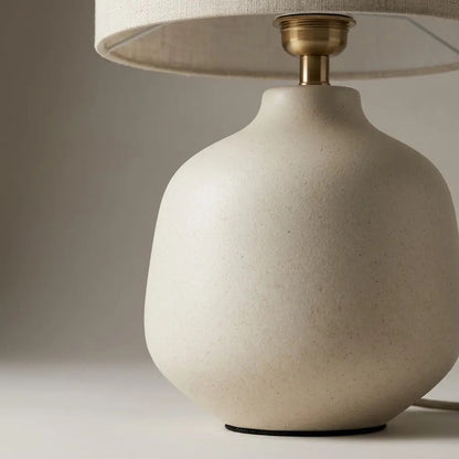 Ivory ceramic table lamp lit in a calm interior setting