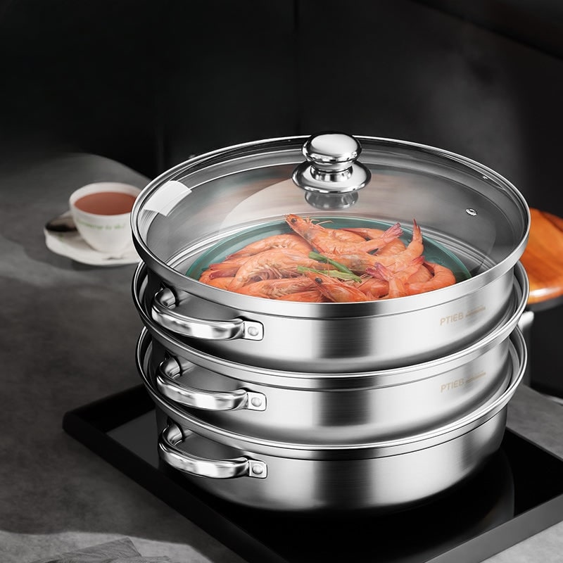 Closed steamer with glass lid on a kitchen counter next to a cup of tea