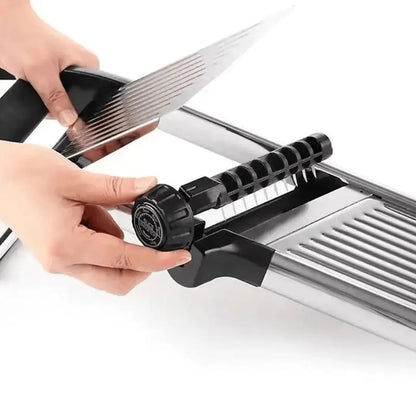Hands turning the dial on the side of the mandoline to change the slice thickness