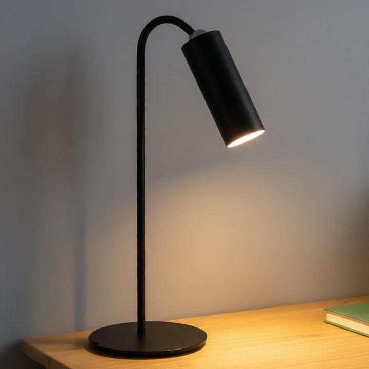 Black desk lamp lighting a wooden desk