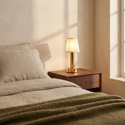 Gold cordless touch table lamp lit on a walnut nightstand in a warm bedroom