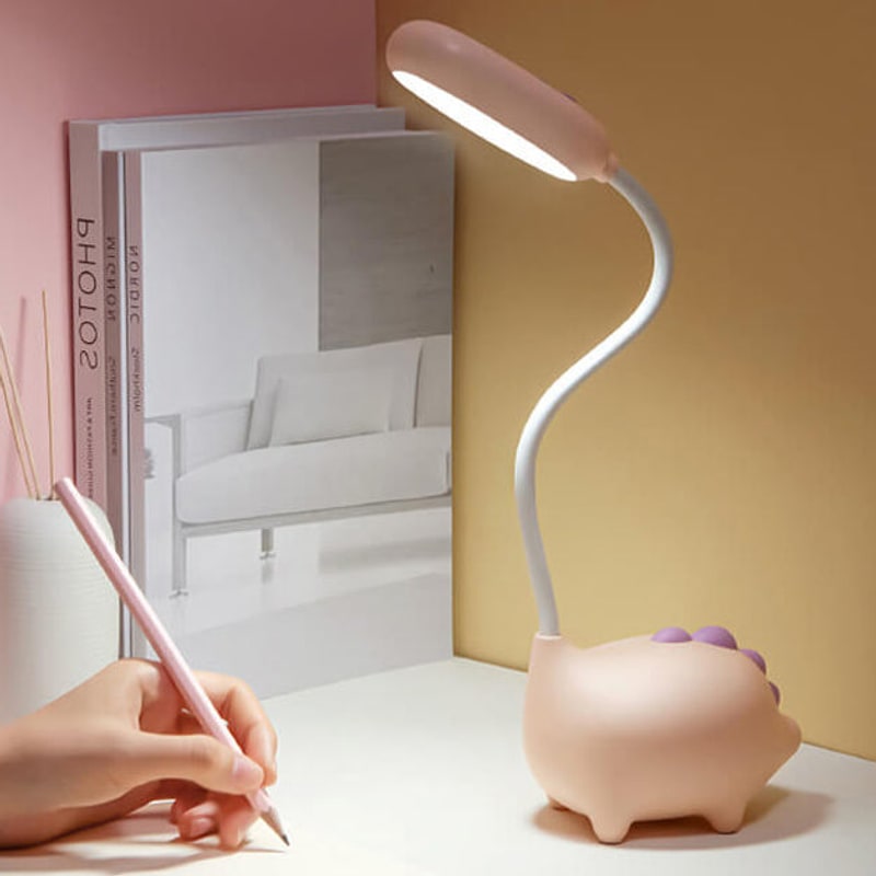 Pink lamp lighting a desk while a child writes