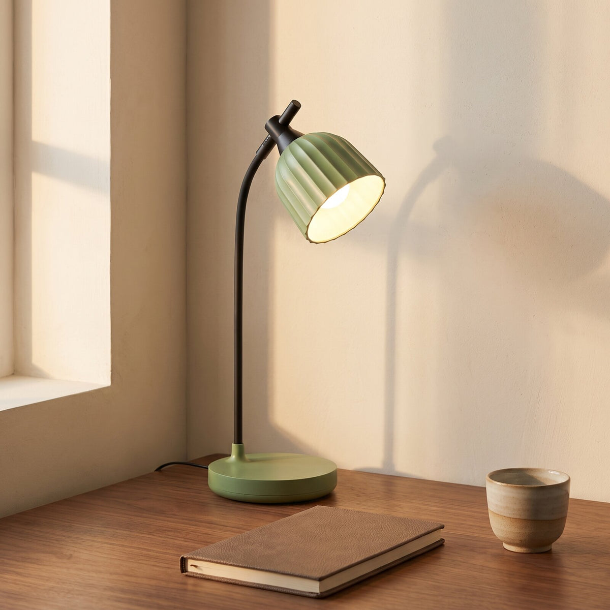 Green foldable LED table lamp lit on a walnut desk in a home office