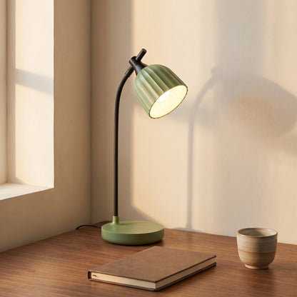 Green foldable LED table lamp lit on a walnut desk in a home office