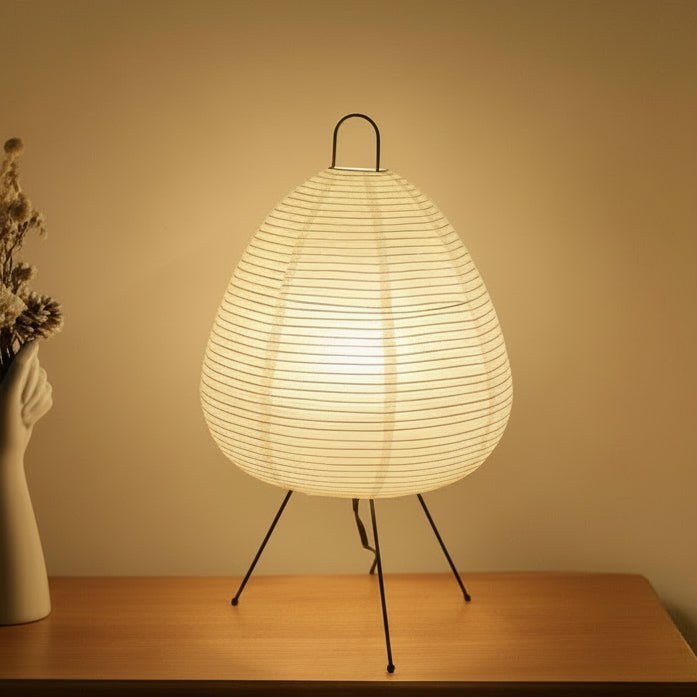 White rice paper table lamp glowing on a wooden table