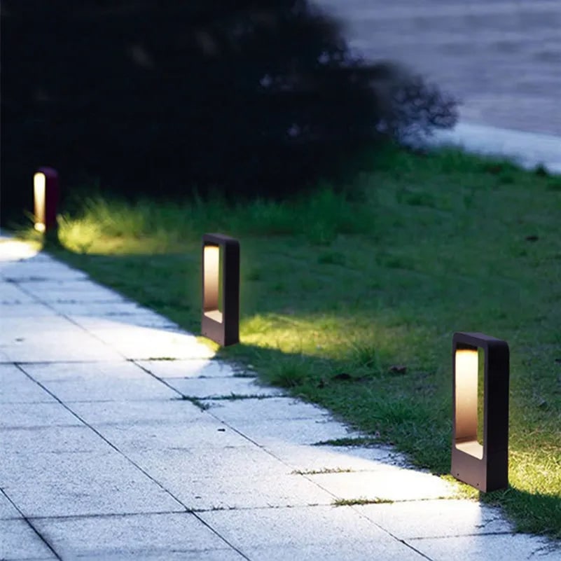 Three black LED bollard lights lighting a stone garden path at dusk