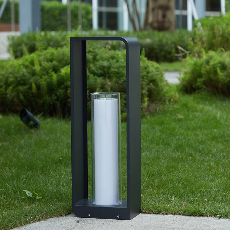 Tall black lantern with clear glass cylinder on a garden path by the lawn