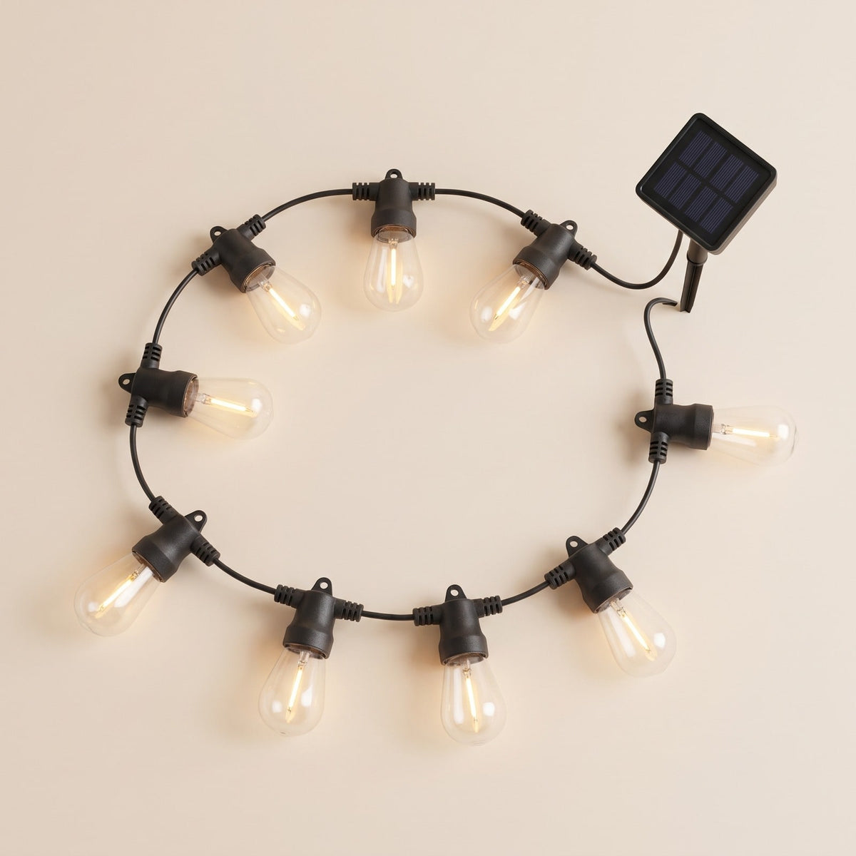 Solar string lights with clear Edison bulbs on a black cable and a small solar panel