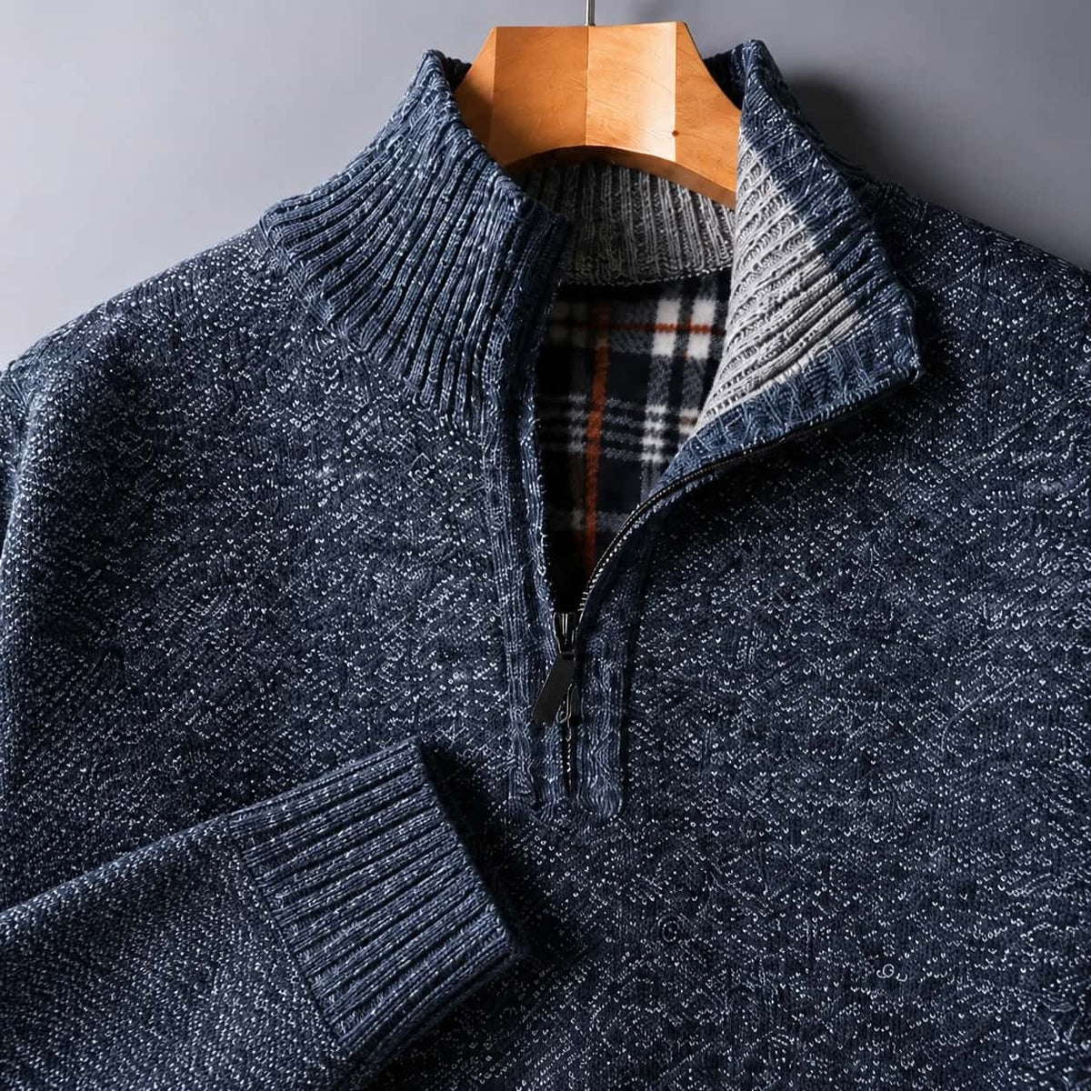Close-up of the blue knit, quarter zip and plaid-lined collar