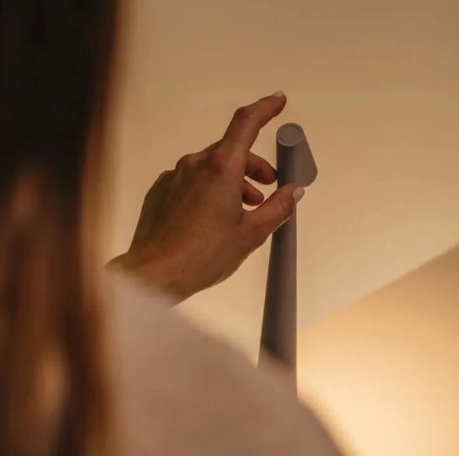 Hand adjusting the tilted head of the slim cordless LED table lamp