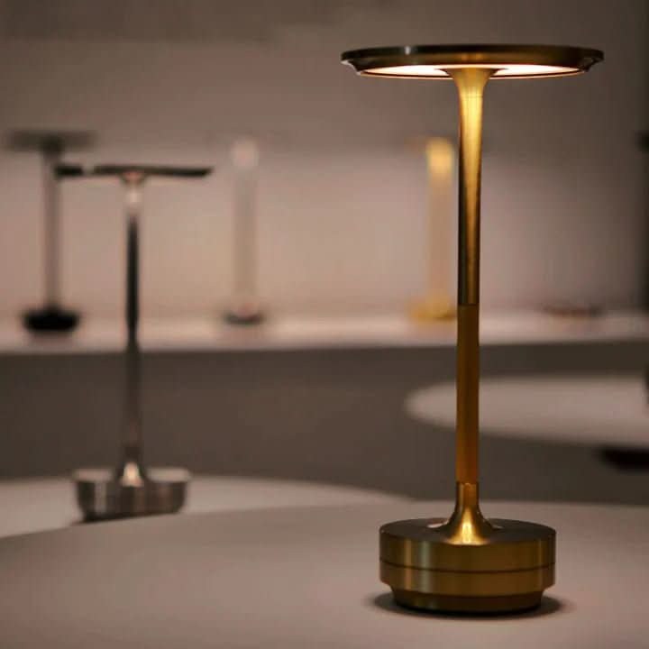 Gold disc LED table lamp switched on