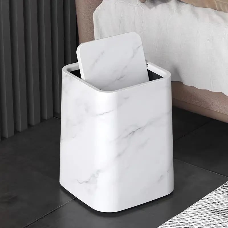 White marble trash can next to a bed