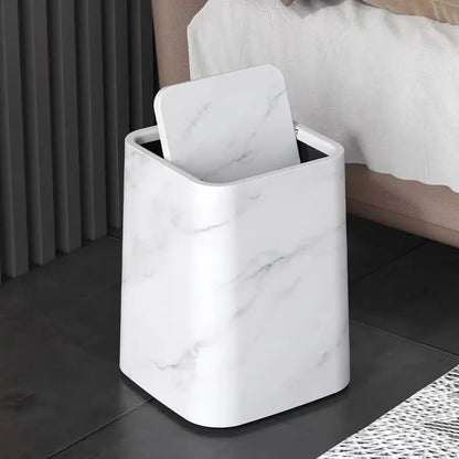 White marble trash can next to a bed