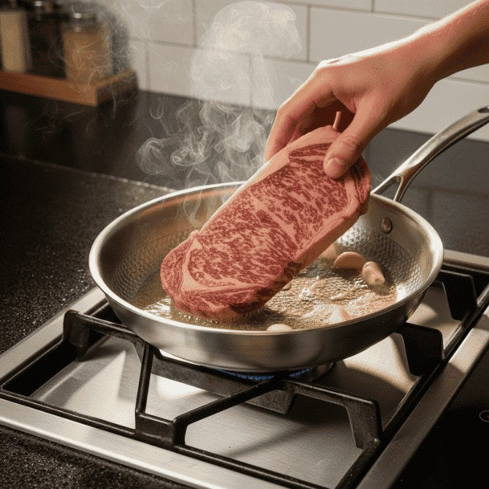 Placing a steak in the hot stainless steel pan