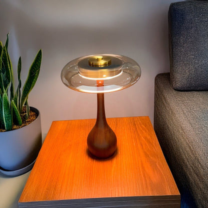 Glass disc LED table lamp glowing on a side table