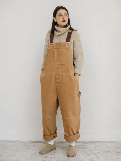 Woman wearing beige canvas bib overalls