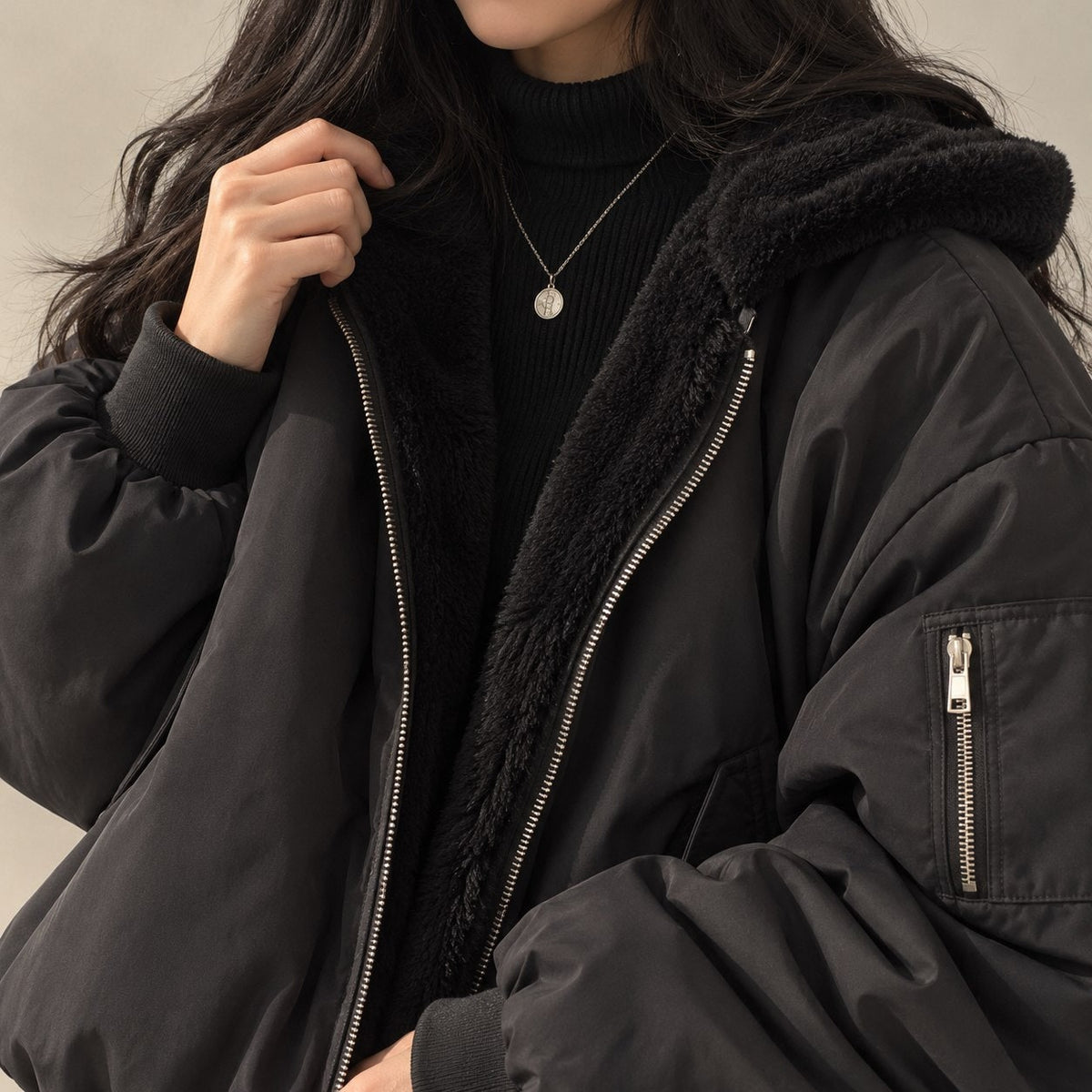 Black reversible jacket, close-up of the zip and sleeve pocket