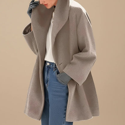 Woman wearing a taupe oversized A-line coat with a wide collar