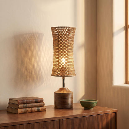 Woven fibre table lamp lit on a walnut sideboard in a reading corner